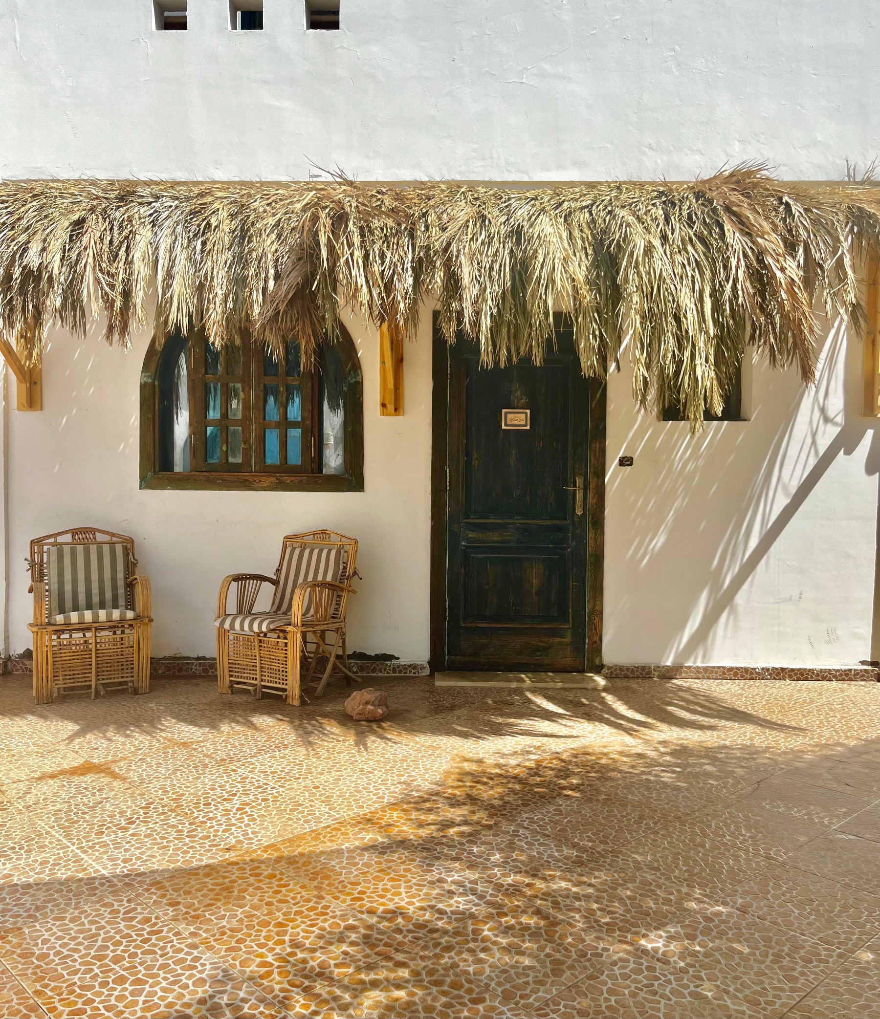Thatched porch with two wooden chairs at the front door