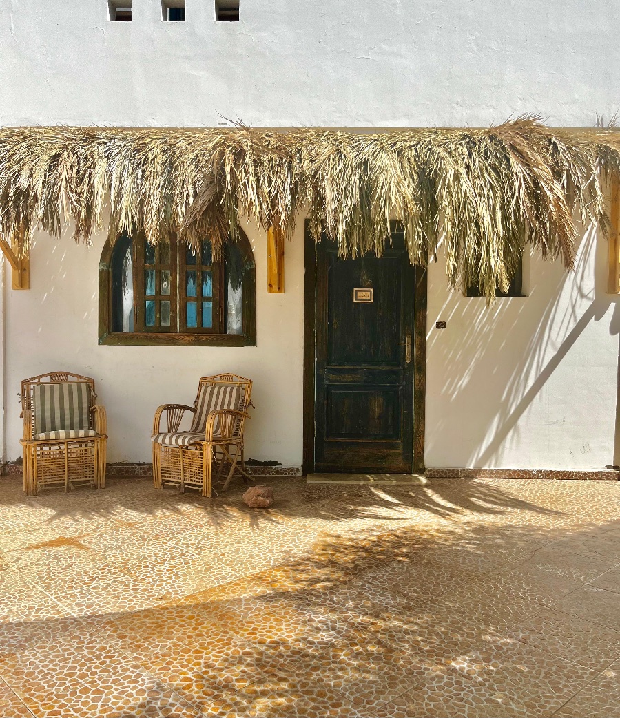 Thatched porch with two wooden chairs at the front door