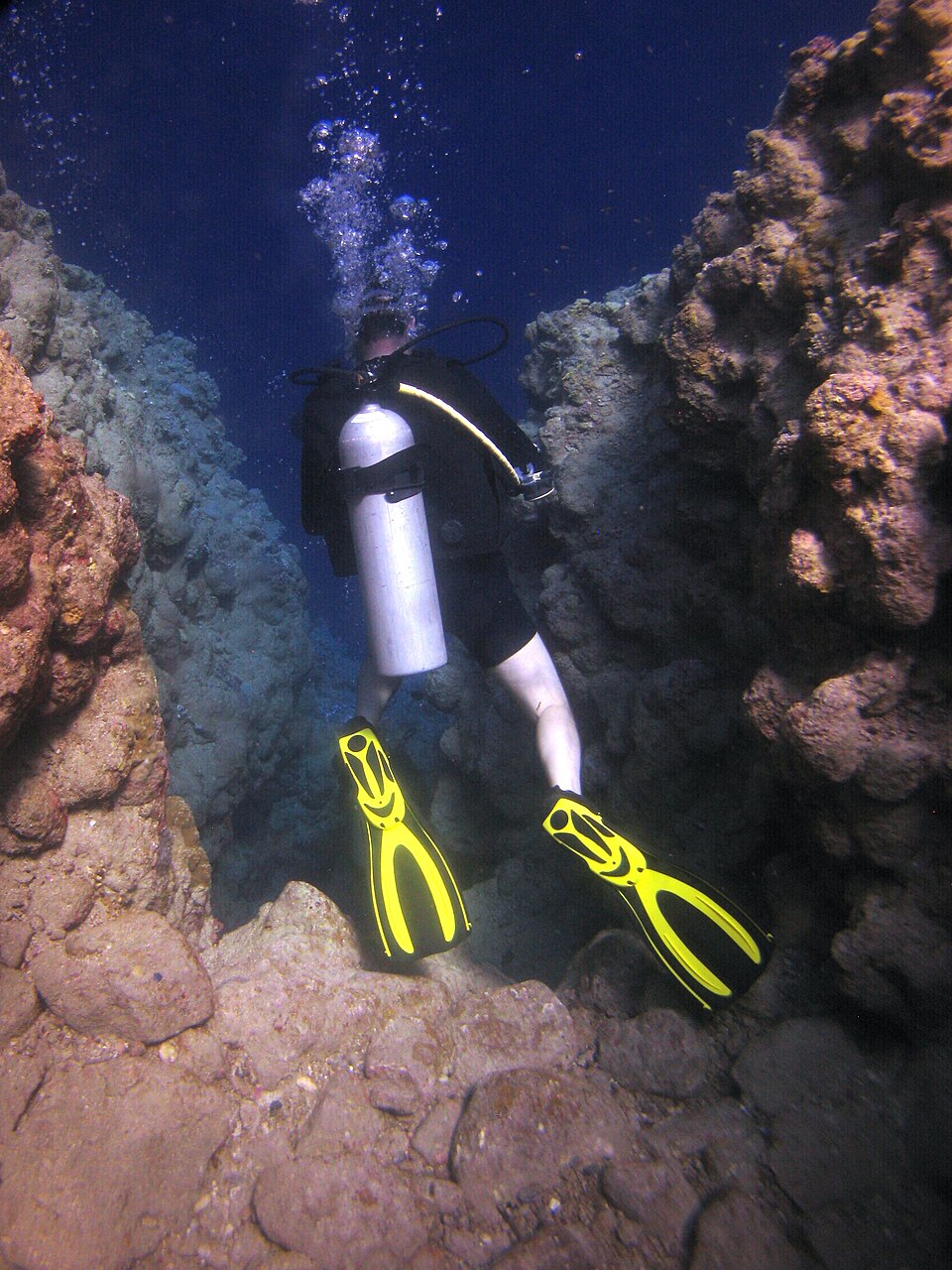 A scuba diver in a gap between coral walls at a Dahab dive site